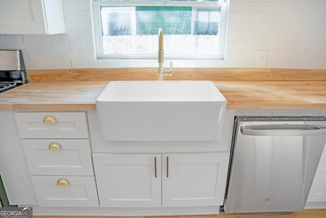 kitchen featuring wooden counters, stainless steel dishwasher, a sink, and a wealth of natural light