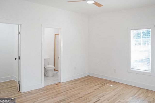 unfurnished bedroom with light wood-style floors, ensuite bath, baseboards, and a walk in closet