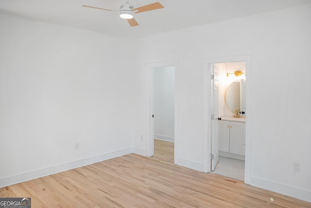 unfurnished bedroom featuring light wood-style flooring, a spacious closet, baseboards, and ensuite bathroom