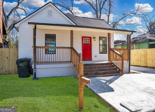 bungalow-style house with roof with shingles, a porch, a front lawn, and fence