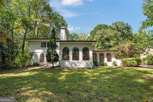 rear view of property featuring a lawn