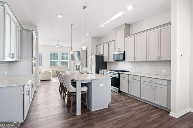 kitchen with stainless steel appliances, gray cabinets, a kitchen island with sink, and sink