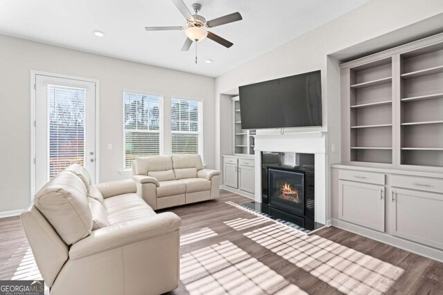 living room featuring vaulted ceiling, ceiling fan, built in features, and dark hardwood / wood-style floors