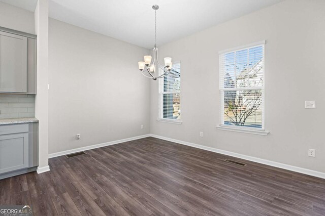 unfurnished dining area featuring dark hardwood / wood-style floors and an inviting chandelier