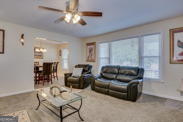 carpeted living room featuring ceiling fan with notable chandelier and plenty of natural light