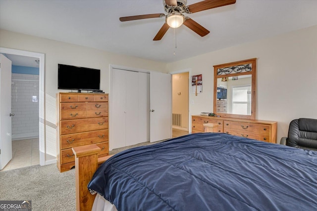 carpeted bedroom with ensuite bath, a closet, and ceiling fan