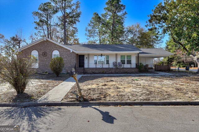 ranch-style home featuring a carport and a porch