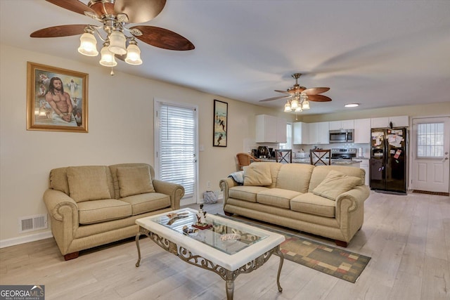 living room featuring ceiling fan and light hardwood / wood-style floors