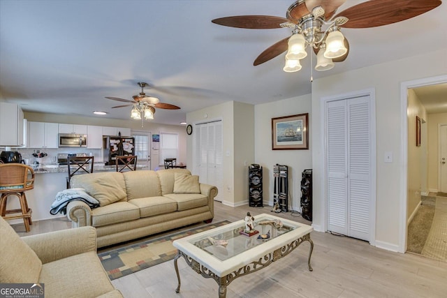 living room featuring ceiling fan and light hardwood / wood-style flooring