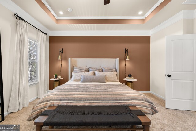 carpeted bedroom with ceiling fan, a raised ceiling, and crown molding