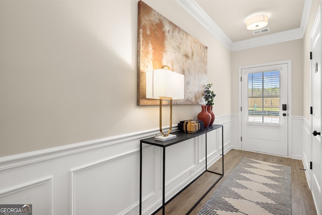 doorway with hardwood / wood-style floors and crown molding