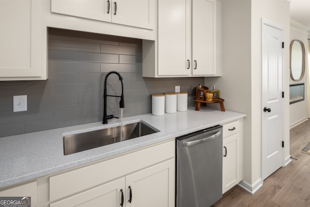 kitchen featuring light stone countertops, tasteful backsplash, stainless steel dishwasher, sink, and light hardwood / wood-style floors