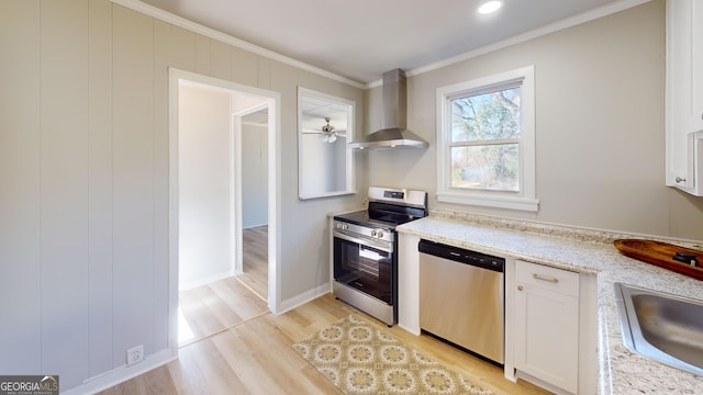 kitchen with sink, wall chimney exhaust hood, ornamental molding, white cabinetry, and stainless steel appliances