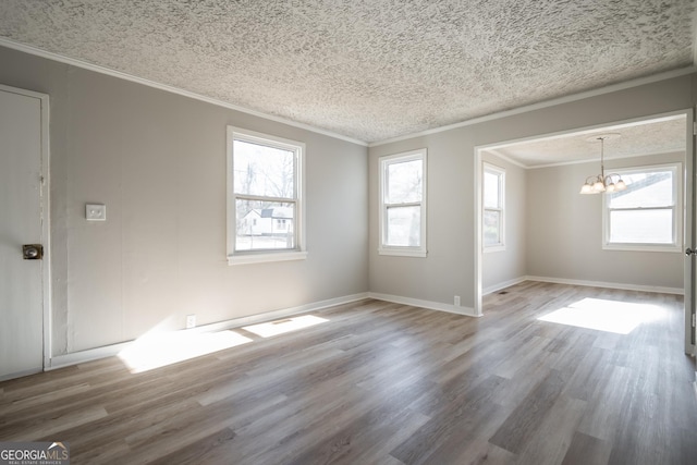 unfurnished room featuring a chandelier, wood-type flooring, and a wealth of natural light