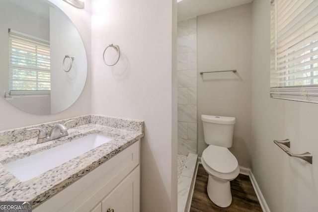 bathroom with hardwood / wood-style flooring, vanity, toilet, and walk in shower