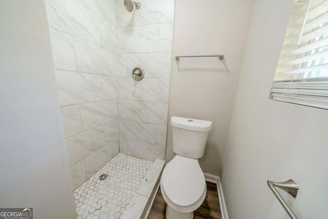 bathroom with a tile shower and toilet