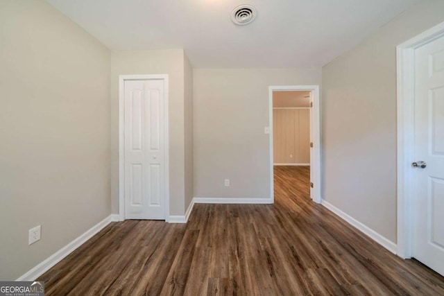 unfurnished bedroom featuring dark hardwood / wood-style flooring and a closet