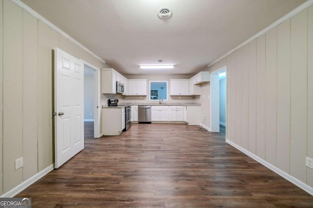 kitchen with white cabinets, sink, ornamental molding, dark hardwood / wood-style flooring, and stainless steel appliances