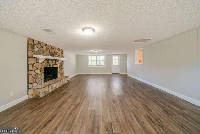 unfurnished living room featuring a fireplace, dark hardwood / wood-style flooring, and a textured ceiling