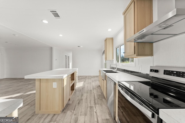 kitchen with a center island, wall chimney range hood, sink, light brown cabinetry, and stainless steel appliances