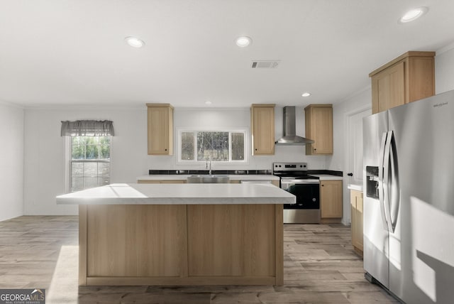 kitchen featuring a center island, sink, wall chimney exhaust hood, light wood-type flooring, and stainless steel appliances