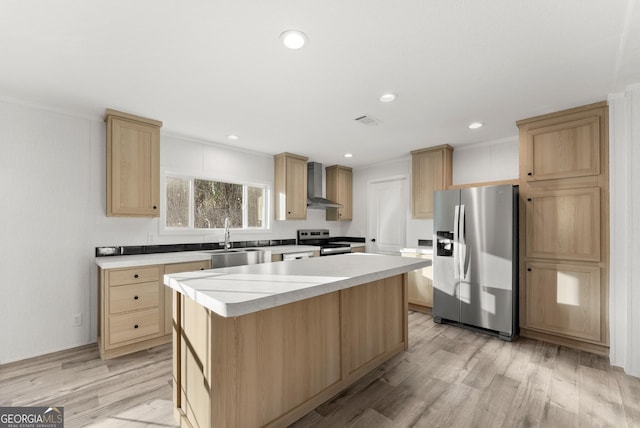 kitchen featuring appliances with stainless steel finishes, light wood-type flooring, sink, wall chimney range hood, and a kitchen island