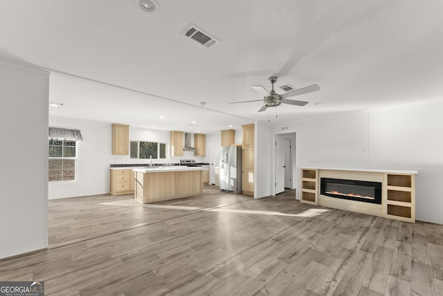 unfurnished living room featuring light wood-type flooring, ceiling fan, and sink