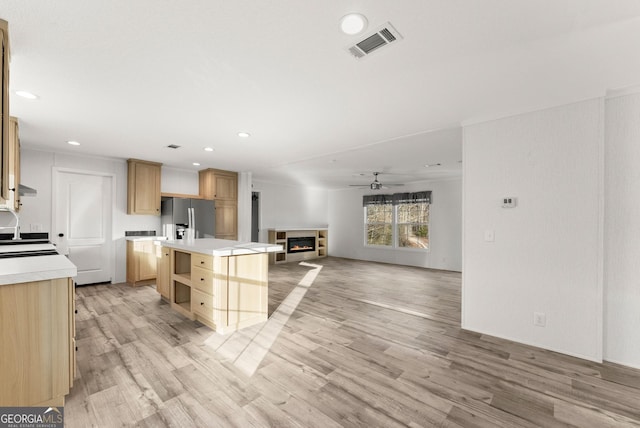 kitchen with ceiling fan, light brown cabinets, light hardwood / wood-style flooring, stainless steel fridge, and a kitchen island