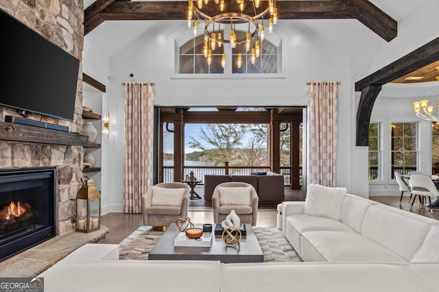 living room featuring a chandelier, high vaulted ceiling, a stone fireplace, and beamed ceiling