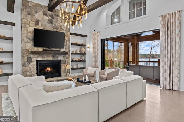 living room with a fireplace, a chandelier, built in features, and light hardwood / wood-style floors