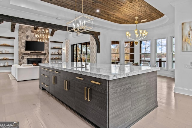 kitchen featuring a fireplace, decorative light fixtures, a raised ceiling, and a large island