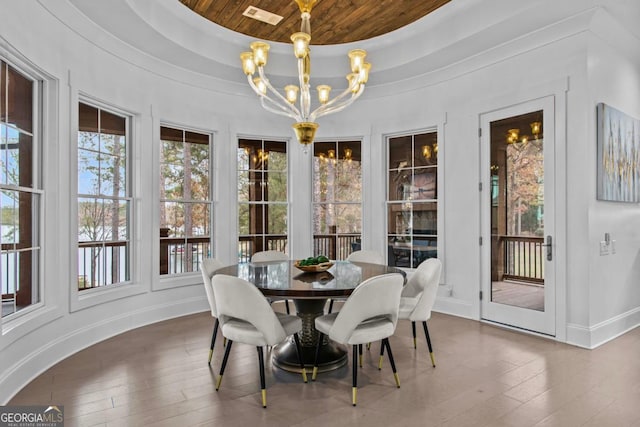 dining space featuring a notable chandelier, dark hardwood / wood-style floors, wooden ceiling, and a tray ceiling