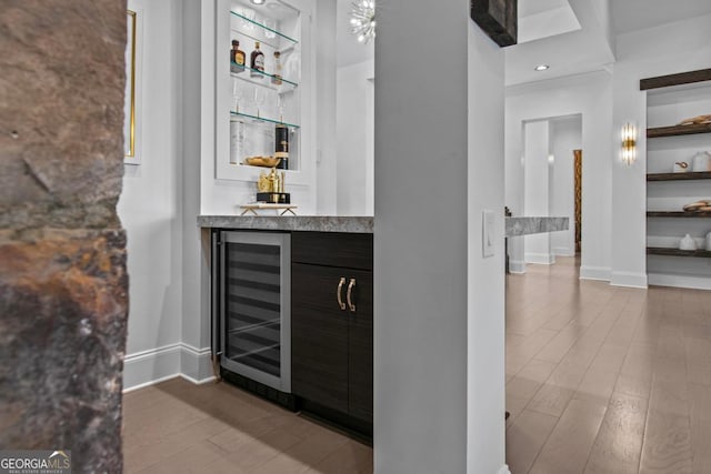 bar with hardwood / wood-style flooring, built in features, and wine cooler