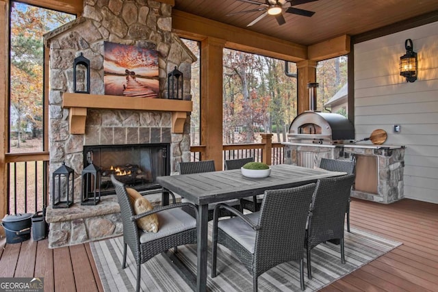 sunroom featuring an outdoor stone fireplace, ceiling fan, and wood ceiling