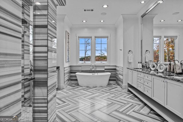 bathroom with a tub to relax in, vanity, and ornamental molding