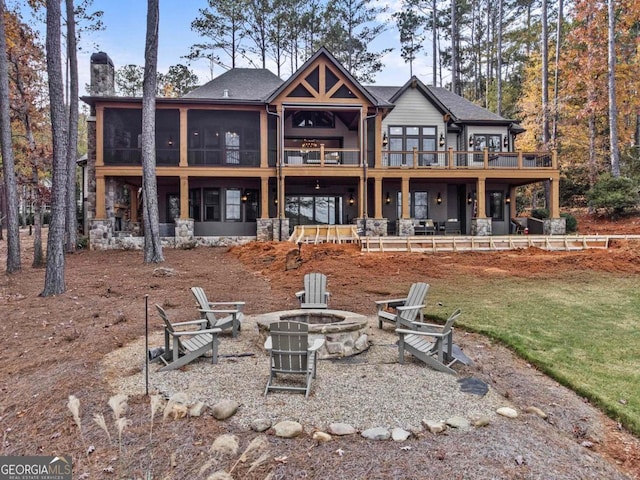 rear view of property featuring a fire pit, a sunroom, and a yard