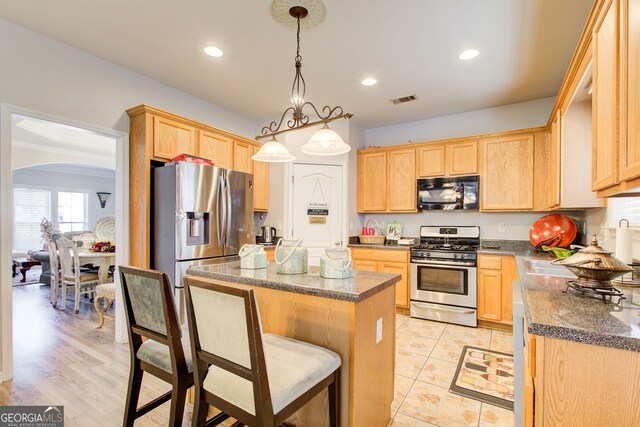 kitchen featuring stainless steel appliances, a center island, and light brown cabinets