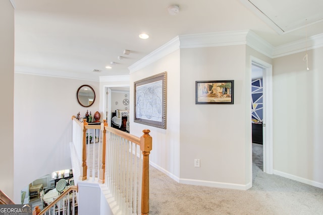 corridor featuring an upstairs landing, attic access, ornamental molding, and carpet flooring