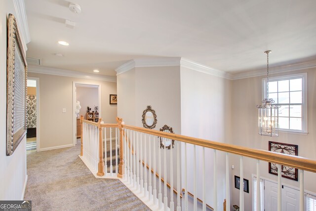 hallway featuring an upstairs landing, an inviting chandelier, carpet flooring, crown molding, and baseboards