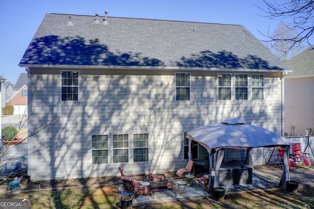 back of property featuring a patio area, outdoor lounge area, a shingled roof, and a gazebo