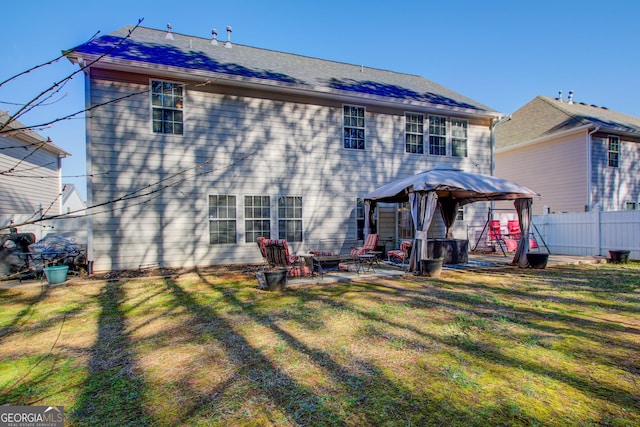 rear view of property featuring a patio, fence, an outdoor fire pit, a gazebo, and a lawn