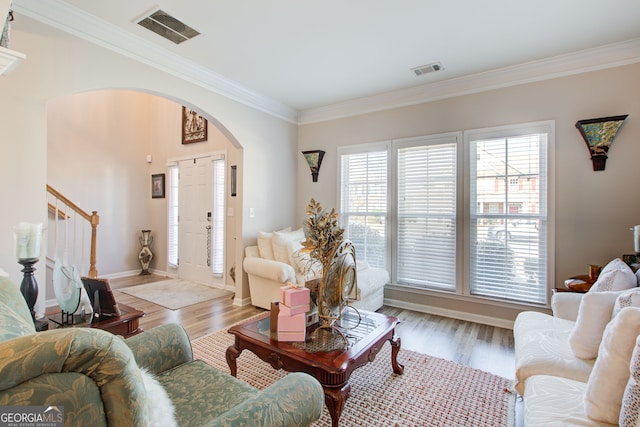 living room featuring arched walkways, visible vents, and wood finished floors