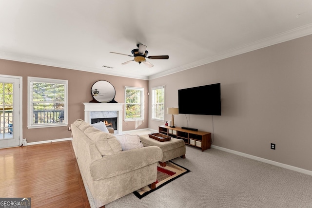 living room featuring ceiling fan, light colored carpet, a premium fireplace, and ornamental molding