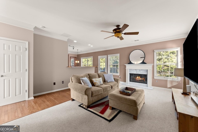 living room featuring ceiling fan with notable chandelier, a fireplace, ornamental molding, and a healthy amount of sunlight