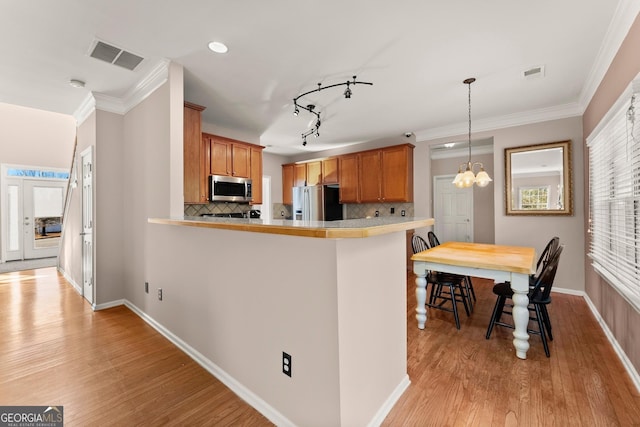 kitchen with tasteful backsplash, a chandelier, kitchen peninsula, and stainless steel appliances