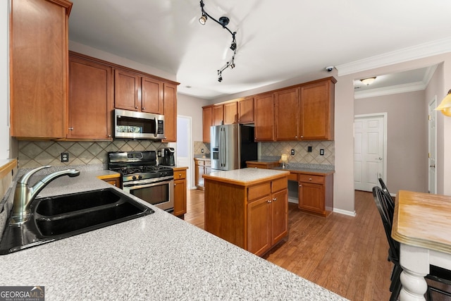 kitchen featuring backsplash, a center island, sink, crown molding, and appliances with stainless steel finishes