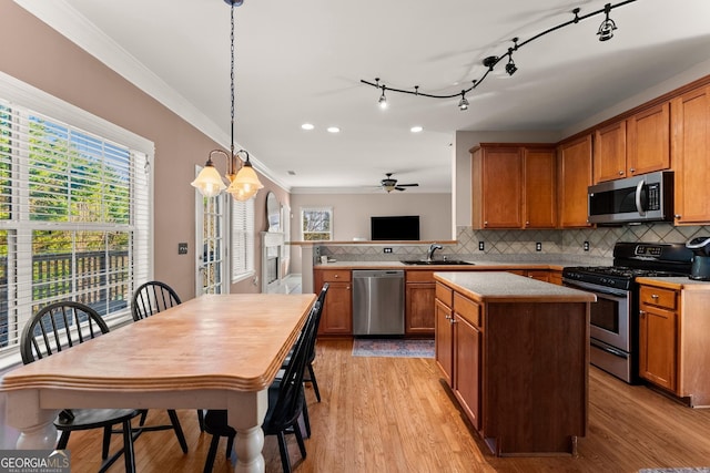 kitchen with pendant lighting, decorative backsplash, sink, appliances with stainless steel finishes, and ceiling fan with notable chandelier