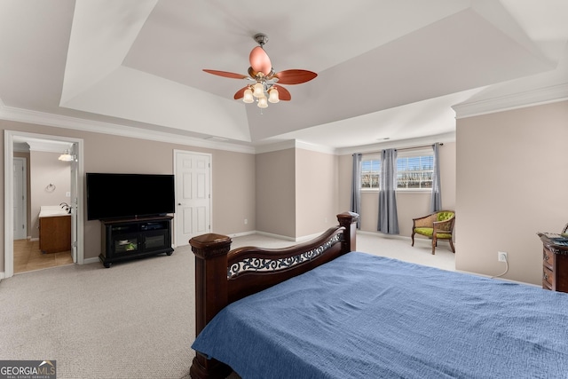 carpeted bedroom featuring ceiling fan, ensuite bathroom, crown molding, and a raised ceiling