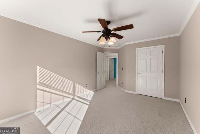 spare room featuring ceiling fan, crown molding, and light carpet