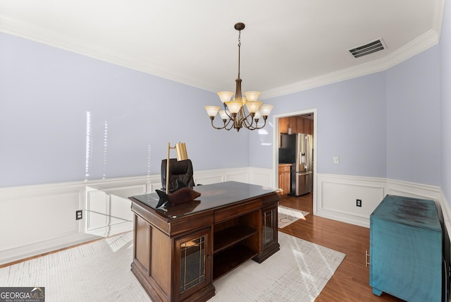 home office with hardwood / wood-style floors, crown molding, and a notable chandelier